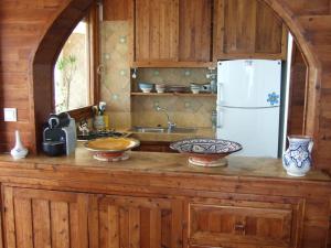 cocina con armarios de madera y nevera blanca en taghazout playa, en Taghazout