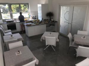a kitchen with tables and chairs and a person in the kitchen at Roseto Mare B&B in Roseto Capo Spulico