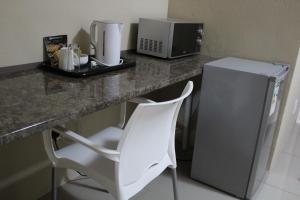 a white chair sitting in front of a counter with a microwave at M n M Guesthouse In Turfloop Mankweng in Polokwane