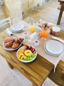 einen Tisch mit Teller mit Lebensmitteln und Obst darauf in der Unterkunft Le tre colonne in Melendugno