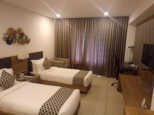 a hotel room with two beds and a television at HOTEL SAVITHRI in Attingal