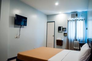 a bedroom with a bed and a tv on the wall at Seasons Hotel Sablayan in Buenavista