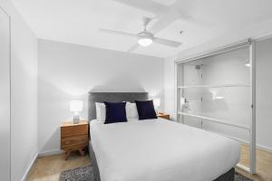 a bedroom with a white bed with blue pillows at Melbourne Holiday Apartments Flinders Wharf in Melbourne