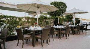 un restaurante con mesas, sillas y sombrillas en City Premiere Hotel Apartments - Dubai en Dubái