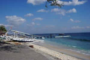 a boat sitting on the beach next to the ocean at Pondok Kana And Hostel by Ecommerceloka in Nusa Penida