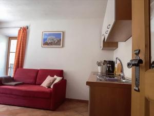 un salon avec un canapé rouge dans une cuisine dans l'établissement Paulnhof, à Brennero