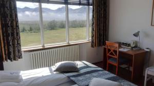Schlafzimmer mit einem Bett, einem Schreibtisch und einem Fenster in der Unterkunft Hotel Stadarborg in Breiðdalsvík
