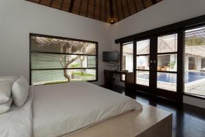 a bedroom with a white bed and two windows at Bvilla Spa in Seminyak