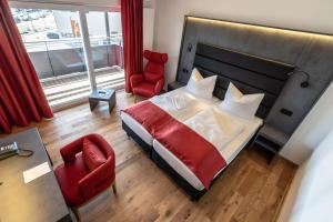 a bedroom with a bed and a red chair at Augsburg Hotel Sonnenhof in Gersthofen