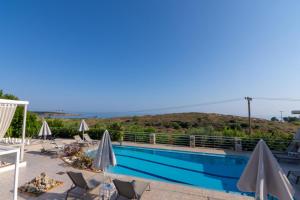 a beach with a pool and a balcony overlooking the ocean at Frida Apartments in Chania