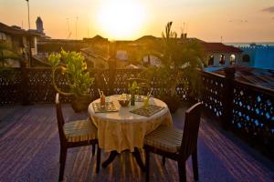 einen Tisch und Stühle auf einem Balkon mit Blick auf den Sonnenuntergang in der Unterkunft Asmini Palace Hotel in Zanzibar City