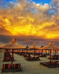 a group of chairs and straw umbrellas on a beach at Splendid Aparthotel in Năvodari
