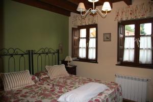 a bedroom with a bed and two windows at Hotel rural La Llastra in Nueva de Llanes