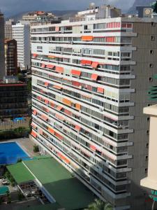 a tall building with a tennis court in front of it at Apartamentos Cervantes in Benidorm