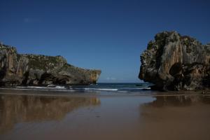 ein Strand mit zwei großen Felsen und dem Ozean in der Unterkunft Hotel rural La Llastra in Nueva de Llanes