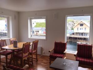 un restaurante con mesa, sillas y 2 ventanas en Lovely 3 rooms apartment for holiday in Nyksund, en Nyksund