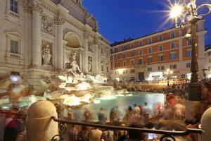 tłum ludzi stojących wokół fontanny w mieście w obiekcie Grand Tour Rome Apartment - Liberty Collection w Rzymie