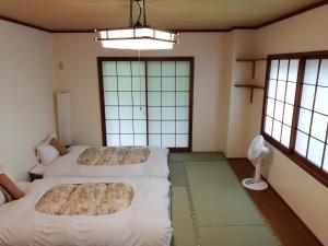 two beds in a room with two windows at Tenjin Lodge in Minakami