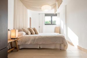 a white bedroom with a bed and a window at Nyumba ya Sun in Cala Tarida