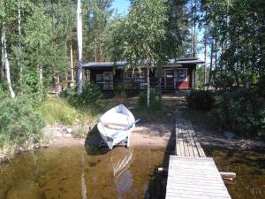 a boat sitting on the water in front of a cabin at Takalahti Lodge in Puumala