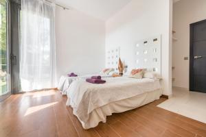a white bedroom with two beds and a large window at Nyumba ya Sun in Cala Tarida