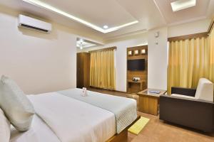 1 dormitorio con 1 cama, 1 silla y TV en Hotel Royal Palace, en Vadodara