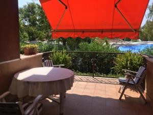 un patio con mesa, sillas y sombrilla roja en alloggio a 200mt. dal mare, en Diano Marina