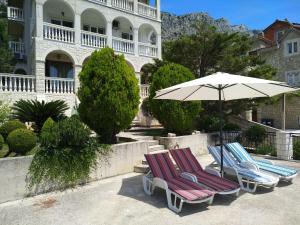 three lounge chairs and an umbrella in front of a building at Apartman Horizont in Omi&scaron;