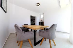 a dining room with a wooden table and gray chairs at Apartman Dana in Zadar