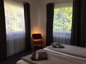 Vitaby Järnvägshotell في Vitaby: غرفة نوم بسريرين وكرسي ونوافذ
