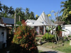 a white house with a garden in front of it at La Casa Homestay in Senggigi 