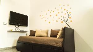 a bedroom with a couch with a tree on the wall at Il Nido del Gabbiano in Bagheria