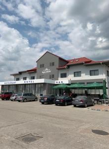 a large building with cars parked in a parking lot at Magnific Hotel in Borş