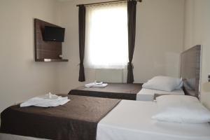 two beds in a hotel room with a window at OTEL SERKAN in Isparta