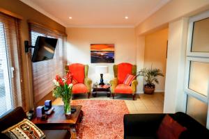a living room with red chairs and a table at Secret Garden Guesthouse in Bloubergstrand