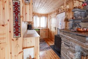 a kitchen with a stone fireplace in a log cabin at Langlofonna in Stranda