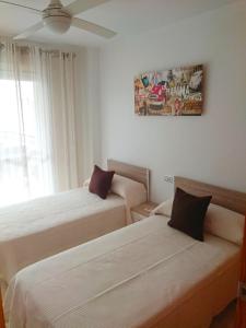 een slaapkamer met 2 bedden en een schilderij aan de muur bij Fantastico Apartamento con solárium in Los Alcázares