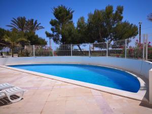 a swimming pool with a white fence and trees at Mare Viva Beach Apartment in Quarteira