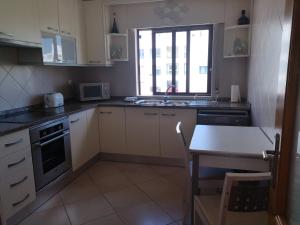 a kitchen with white cabinets and a table and a window at Mare Viva Beach Apartment in Quarteira