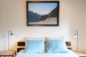 a bedroom with a bed with two blue pillows at B&B MaisonNel in Saint-Bonnet-en-Champsaur