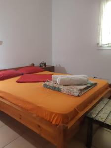 a large bed with orange sheets and pillows on it at Dina in Palaia Fokaia