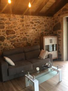 sala de estar con sofá y pared de piedra en O RELAX DO RÍO, en Os Muinos