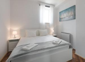 ein weißes Schlafzimmer mit einem großen Bett mit zwei Handtüchern darauf in der Unterkunft City Center Pearl 2 in Zagreb