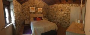 1 dormitorio con 1 cama en una pared de piedra en O RELAX DO RÍO, en Os Muinos