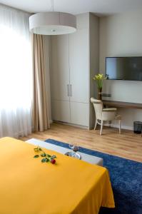Habitación de hotel con cama amarilla y TV. en Ditlin, en Pápa