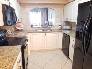 a kitchen with white cabinets and a black refrigerator at Surf Club I, 1405 Condo in Palm Coast +32 photos