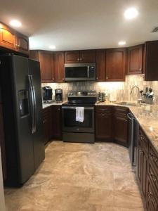 una cocina con electrodomésticos negros y armarios de madera en Summerhouse 101 Condo, en St. Augustine