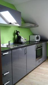 uma cozinha com um fogão, um lavatório e um micro-ondas em en gaume séjour au calme em Jamoigne