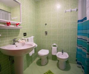 W wyłożonej zielonymi kafelkami łazience znajduje się umywalka i toaleta. w obiekcie B&B A Modo Mio w mieście Marsala