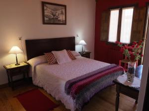 a bedroom with a bed and two tables with lamps at Hostal Almanzor Gredos in Navarredonda de Gredos